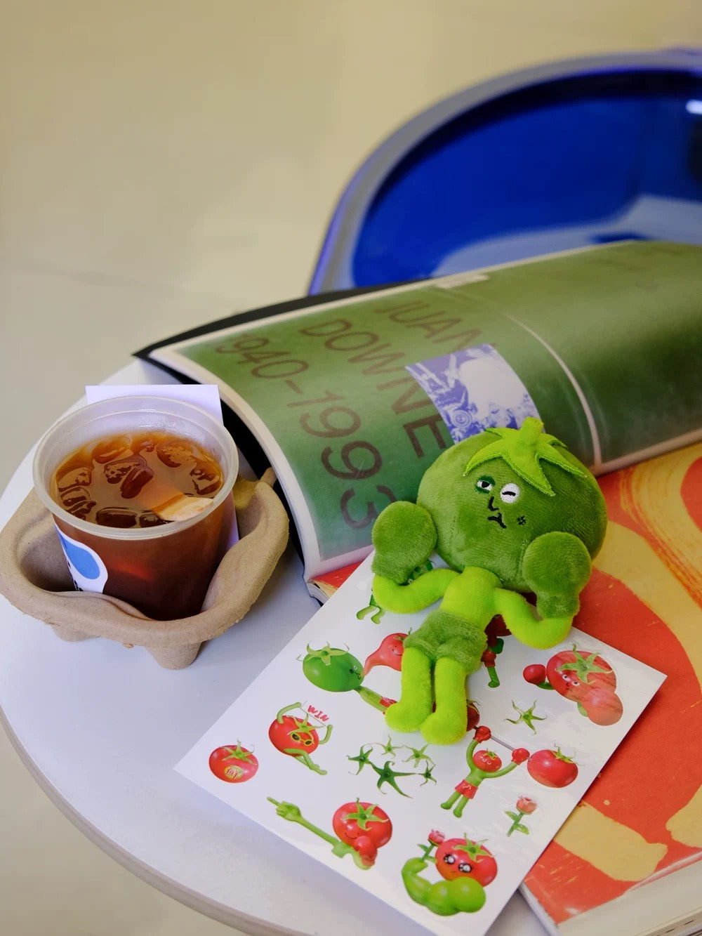Wulibuddy Purr green Boxing Tomato Buddy plush bag  Charm & keychain accessory on a table with a cup of tea and a book