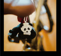 Panda keychain hanging from a guitar with a blurred background