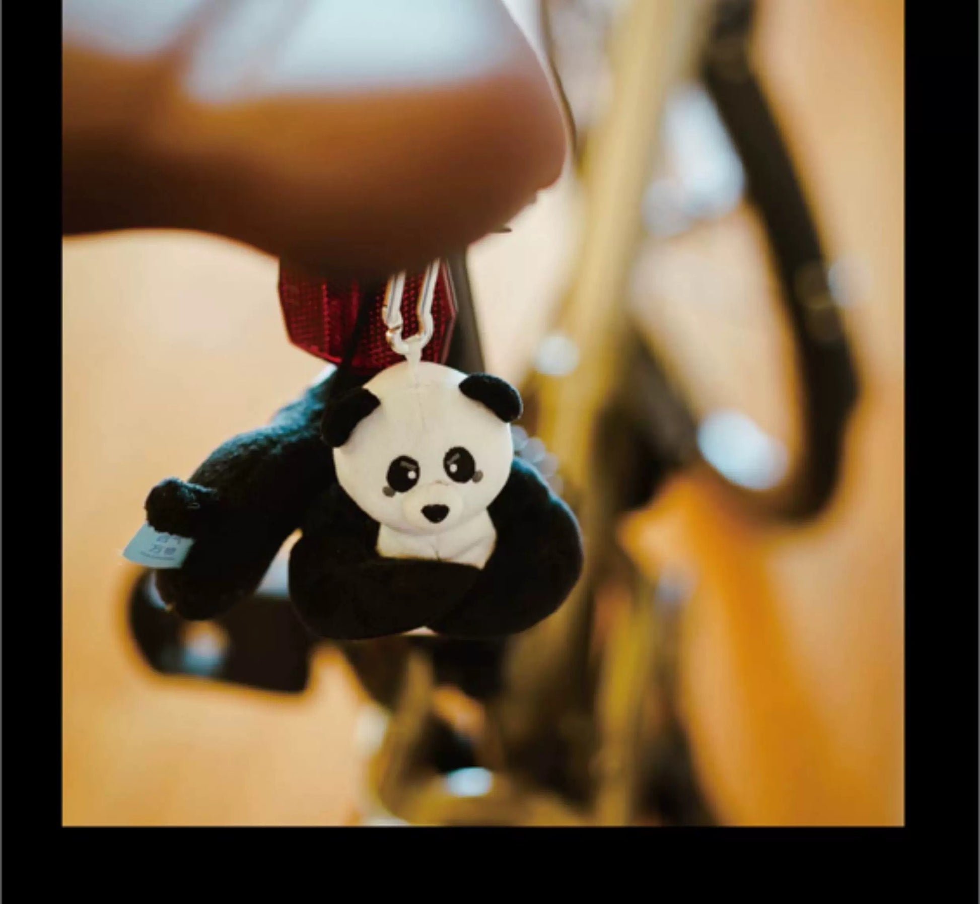 Panda keychain hanging from a guitar with a blurred background
