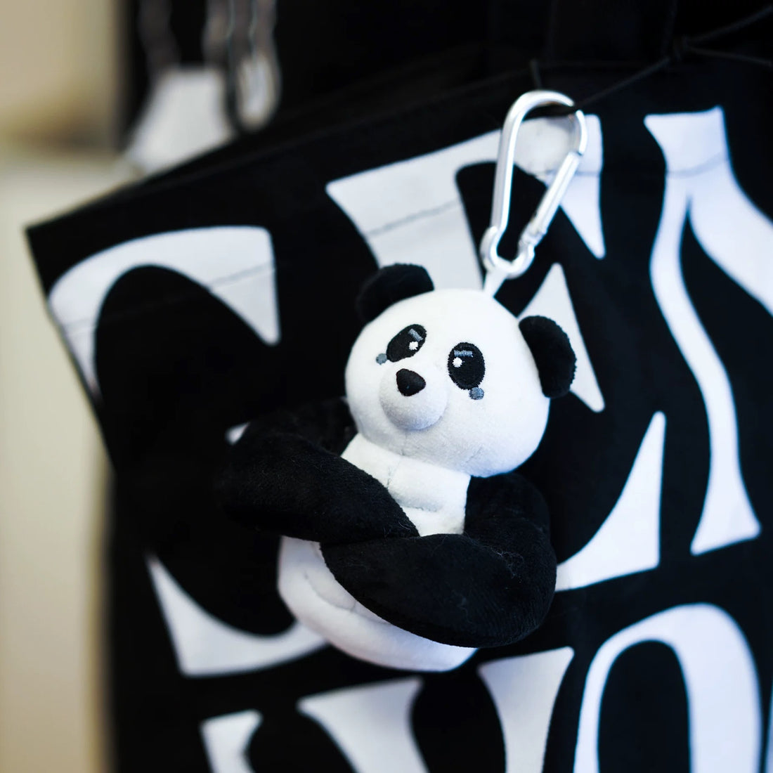 wulibuddy Plush coach  panda keychain & bag charm attached to a black backpack.