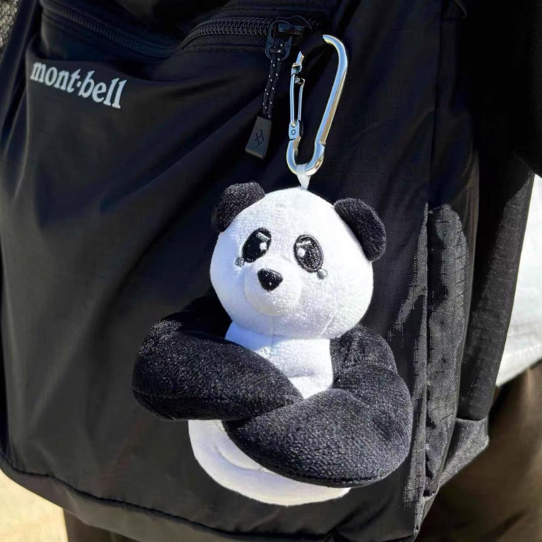 wulibuddy Plush coach  panda keychain & bag charm attached to a black backpack.